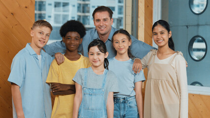 Happy teacher and diverse student standing while smilling to camera. Professional smart instructor with highschool children with mixed races in casual outfit pose at camera with cheerful. Edification.