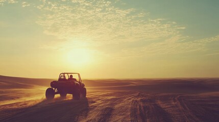 A silhouette of a person driving a dune buggy across a desert landscape at sunset.