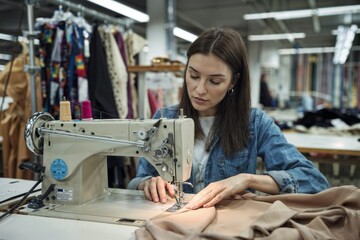 Woman, clothes and fashion designer with sewing machine for retail production or manufacturing garment. Female person, seamstress or dressmaker with material for handmade fabric in small business