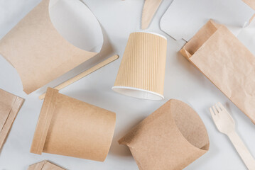 Eco-friendly, biodegradable disposable tableware and cutlery made of paper and wood. Cups, bags, cutlery and food containers for sustainable and environmentally conscious food service. Flat lay