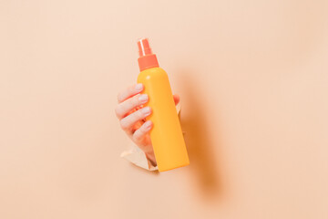 Hand holding cosmetic spray container (for skin or hair). Cosmetic beauty packaging