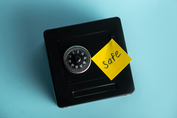 Secure black safe with combination lock and sticky note on blue background