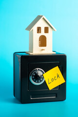 Mini house on safe box with lock sign symbolizing security and protection concept