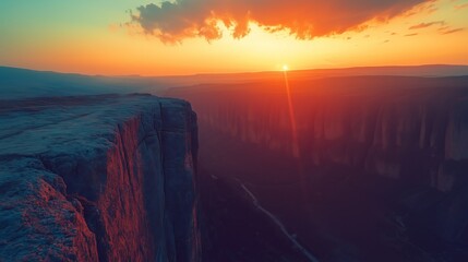 Obraz premium Vibrant Sunset Over Canyon Cliffs with Sun Rays and Deep Valley View