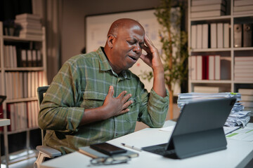 Businessman is suffering chest pain and a headache while working late in his office
