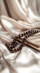Naklejka premium Close-up of prayer beads and a Quran placed on a soft fabric with a light background, symbolizing reflection during Ramadan