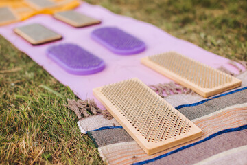 Standing on sadhu board, process of barefoot standing on nails therapy, view of legs feet on nails, yoga and sadhu practice, outdoor meditation with nailing practice, wooden nail board, summer day