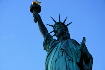 Fototapeta premium Seitliches Profil der Freiheitsstatue, die stolz die Fackel der Freiheit hochhält, vor klarem blauen Himmel; Wahrzeichen und Sehenswürdigkeit von New York, Vereinigte Staaten von Amerika