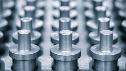 row metal pins are lined up in a row. pins are all the same size and shape, and they are all facing the same direction. image gives off a sense of order and uniformity, industry concept background.