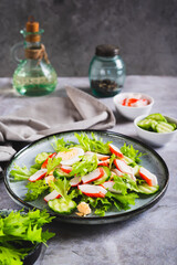Light salad of crab sticks, cucumber, boiled egg and lettuce on a plate on the table vertical view