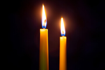 two candles with bright flames at night on a black background, Christmas celebration