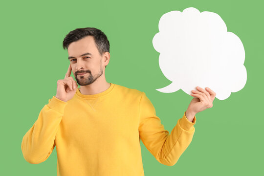 Thoughtful young man with blank speech bubble on green background