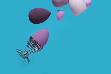 Flying different makeup sponges on blue background