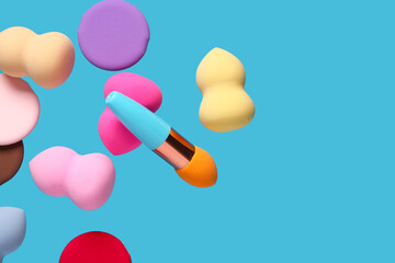 Flying different makeup sponges on blue background
