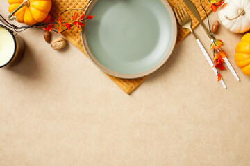 Elegant autumn table setting with a plate, golden cutlery, and festive fall decorations like...