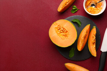 Slate board with tasty ripe melon on red background