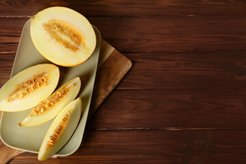 Plate with pieces of sweet melon on wooden background