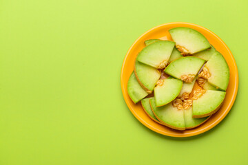 Plate with pieces of sweet melon on green background © Pixel-Shot