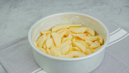 Baking pan with sliced apples close-up on a kitchen table. Apple cake or apple pie recipe
