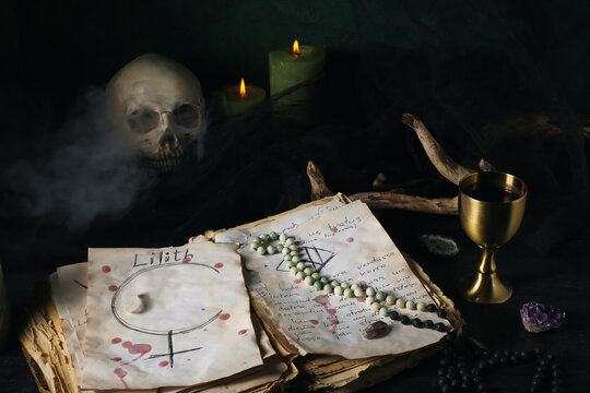 Witch's magic attributes with spell book on dark table