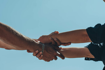 Couple hands held together on blue sky background, close up