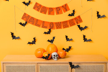 Halloween pumpkins with skull and paper bats on commode in room
