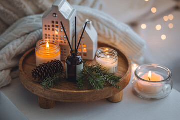 Winter home aromatherapy. Scented aroma candles, fir tree or spruce scent, decorative pine cones on wooden tray. Cozy atmosphere, relaxation, festive mood, interior decor bedroom, living room