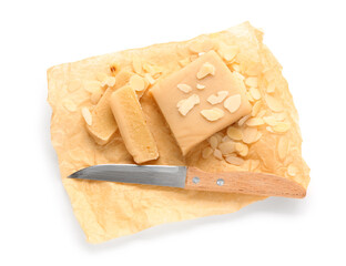 Baking paper with marzipan, almond flakes and knife on white background