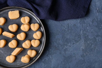 Plate with tasty marzipan candies and napkin on color background