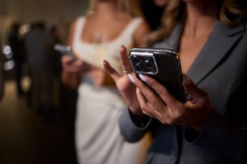 Woman in stylish dress with chic manicure using smartphone in closeup shot