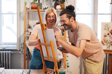 Smiling artists painting together and bonding at creative art studio.