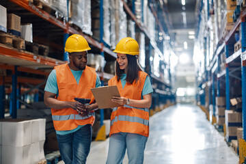 Two diverse warehouse workers sharing a discussion in equipment