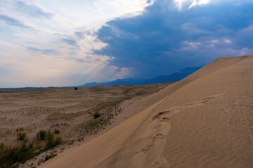 Dramatic desert dunes under sunbeams and cloudy sky