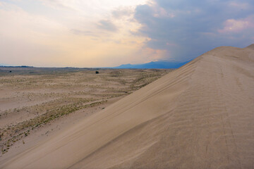 Dramatic desert dunes under sunbeams and cloudy sky