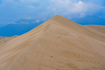 Dramatic desert dunes under sunbeams and cloudy sky