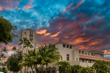 Honolulu City Hall with lush green palm trees and plants and powerful clouds at sunset in downtown Honolulu Hawaii USA