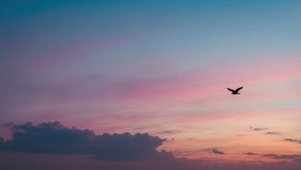 Obraz premium Bird soaring at sunset with pink, purple, and blue sky hues