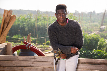 Portrait of a focused African American man at the fence in the backyard of a country house with a...