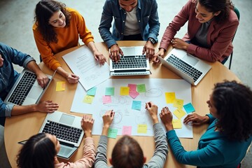 A diverse team engages in a brainstorming session around a table filled with laptops, sticky notes, and papers, representing collaboration, creativity, and planning in a modern workspace.