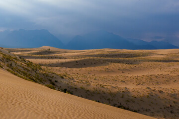 Sunlit desert dunes with dramatic clouds and sunbeams
