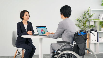 車椅子に乗ってオフィスで仕事する女性ビジネスパーソン