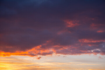 Vibrant sunset sky with dramatic clouds over calm horizon.