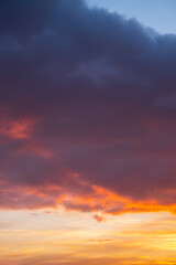 Vibrant sunset sky with dramatic clouds over calm horizon.