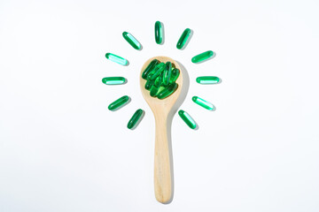 Green pills herbal medicine, Green oil pills Vitamin E, Softgels green in a wooden spoon