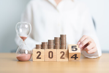 2024 end year to Happy New Year 2025 with hourglass and coins stack arrangement. Money Saving for...