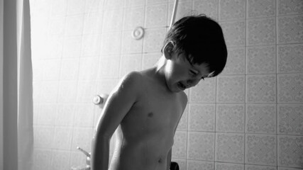 Young boy crying under shower, black and white photo of distressed child during bath time, emotional moment, wet hair and skin, bathroom scene, child hygiene, tears and water droplets