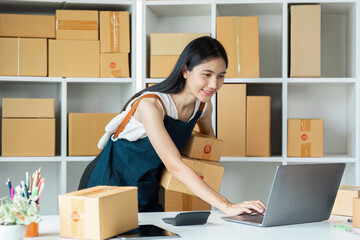 Young Entrepreneur Managing Online Business with Laptop and Shipping Boxes in Modern Workspace