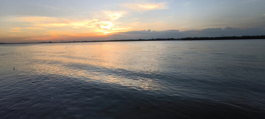 The sun is setting on the river.