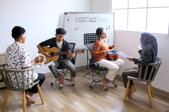 Happy Asian High School Students Learning Playing Musical Instrument And Singing In Class