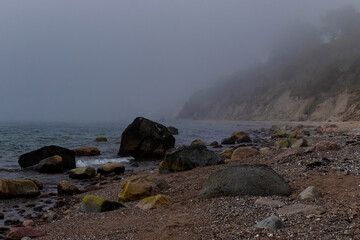 Rocks in the water at a beach in Northern Germany on a foggy spring day.